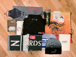 A flatlay of various corporate swag items on a hardwood floor