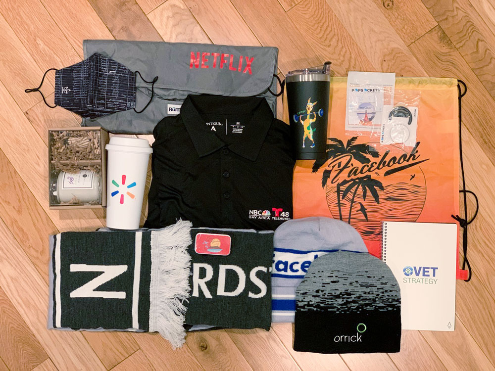 A flatlay of various corporate swag items on a hardwood floor
